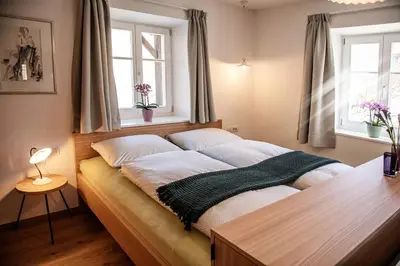a bed in a bedroom with two windows at Puenlandhof in Brunico