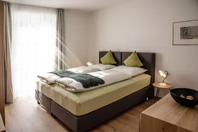a bedroom with a bed with a large window at Puenlandhof in Brunico