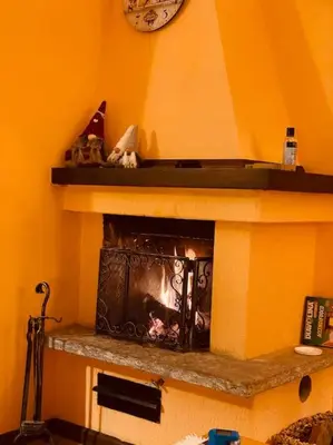 a room with a fireplace with a clock on the wall at Dolomiti Terrace Cavalese in Cavalese