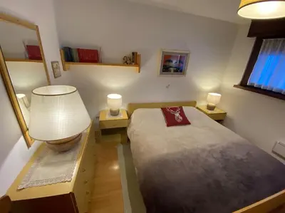 a small bedroom with a bed and two lamps at Dolomiti Terrace Cavalese in Cavalese