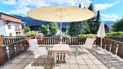 a table and chairs with an umbrella on a patio at Dolomiti Terrace Cavalese in Cavalese