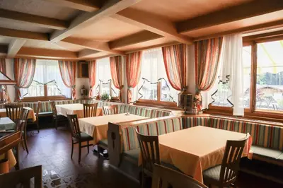 a restaurant with tables and chairs and windows at Gasthof Albergo Neuwirt in Val di Vizze