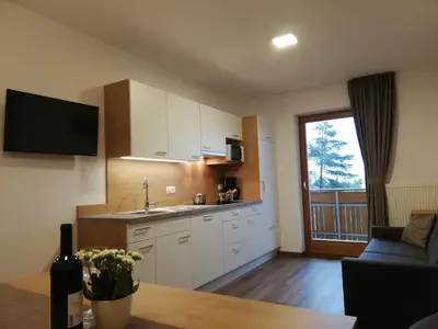a kitchen with white cabinets and a table and a window at Pramstaller Apartments in San Lorenzo di Sebato