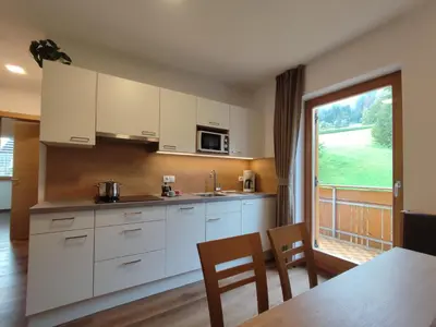 a kitchen with white cabinets and a table and a window at Pramstaller Apartments in San Lorenzo di Sebato