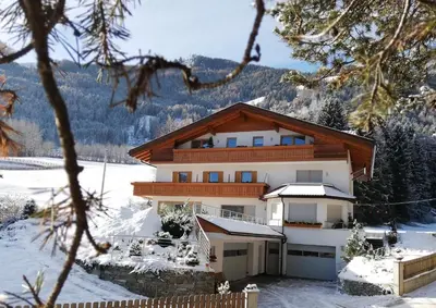 a house in the winter with snow on the ground at Pramstaller Apartments in San Lorenzo di Sebato