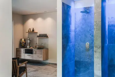 a bathroom with a blue shower and a kitchen at Guesthouse Karnatsch in Parcines