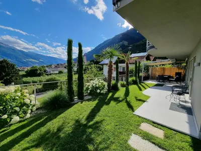 a garden with palm trees and a house at Appartement Mayr in Parcines