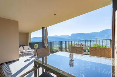 a balcony with a table with a view of the mountains at Apfelhof in Termeno