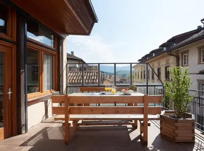 a wooden bench sitting on a balcony with a view at Goldengel Ferienwohnung im Herzen Kalterns mit einer Terasse zum verlieben in Caldaro