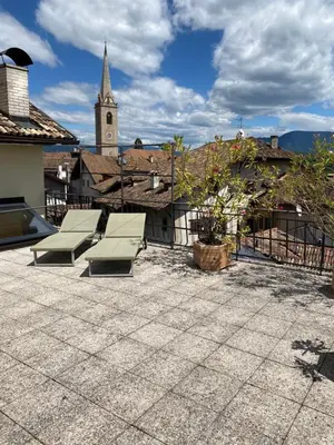 a group of benches sitting on a patio with a church at Goldengel Ferienwohnung im Herzen Kalterns mit einer Terasse zum verlieben in Caldaro
