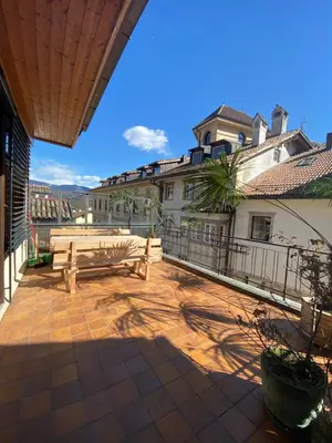 a patio with a wooden bench on a balcony at Goldengel Ferienwohnung im Herzen Kalterns mit einer Terasse zum verlieben in Caldaro