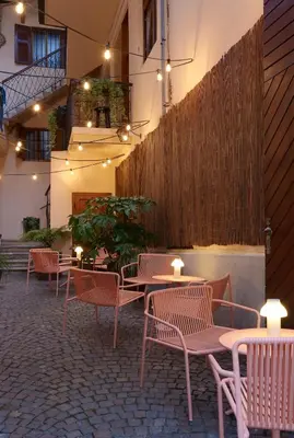 a patio with tables and chairs and a fence at Goldengel Ferienwohnung im Herzen Kalterns mit einer Terasse zum verlieben in Caldaro