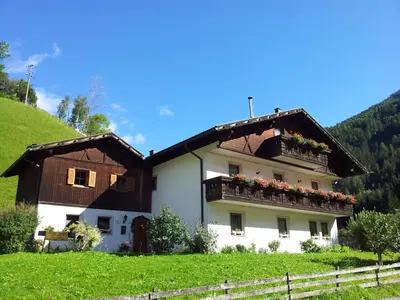 a white house with a balcony on a hill at Ferienhaus-Grünfelder in Luson