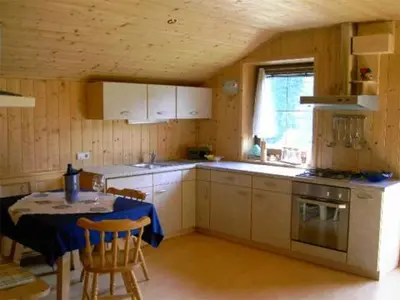 a kitchen with a table and a stove and a table and chairs at Ferienhaus-Grünfelder in Luson