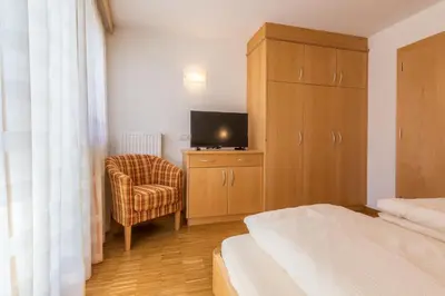 a bedroom with a bed with white sheets and a window at Ciasa Dolomites in La Villa