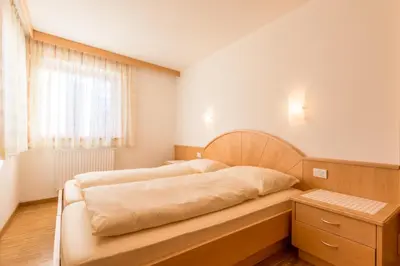 a bedroom with a bed and a tv and a chair at Ciasa Dolomites in La Villa