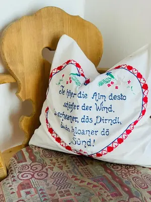 a pillow sitting on a chair with a red and white pillow at Tannerhof Bed & Breakfast in Caines