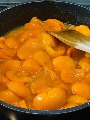 a pot full of orange food with a wooden spoon at Tannerhof Bed & Breakfast in Caines