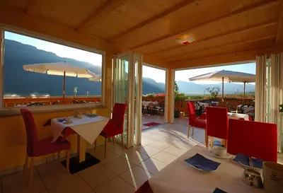 a restaurant with tables and chairs and large windows at Hotel & Residenz Traubenheim in Nalles