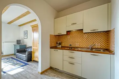 a kitchen with white cabinets and an arched doorway at Hotel & Residenz Traubenheim in Nalles