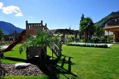 a playground with a slide and a palm tree at Modern Living by Nalserhof in Nalles