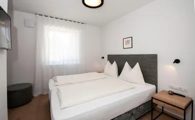 a white bedroom with a large white bed with white pillows at Modern Living by Nalserhof in Nalles