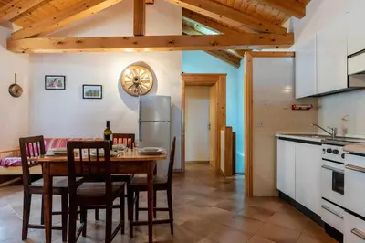 a kitchen and dining room with a table and chairs at Dimora al Portico Cloz OSPITAR in Cloz