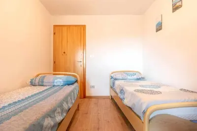 two beds in a small room with a door at Dimora al Portico Cloz OSPITAR in Cloz