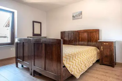 a bedroom with a bed with wooden furniture and a window at Dimora al Portico Cloz OSPITAR in Cloz