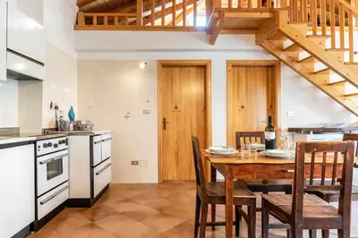 a kitchen with a wooden table with chairs and a staircase at Dimora al Portico Cloz OSPITAR in Cloz