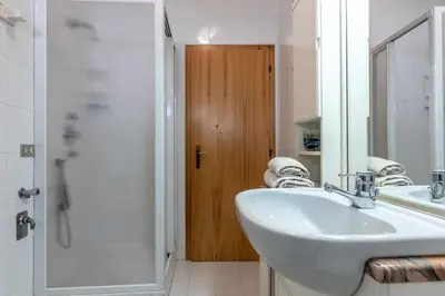 a white bathroom with a sink and a shower at Dimora al Portico Cloz OSPITAR in Cloz
