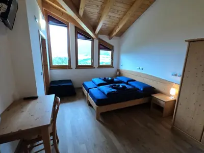 a bedroom with a bed and a table and windows at Agritur Fiore in Fondo