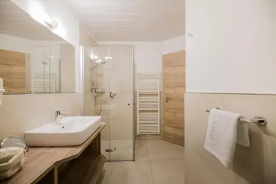 a bathroom with a shower and a toilet and a sink at Apartments Sosaslong in Selva di Val Gardena