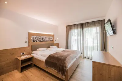 a bedroom with a large bed and a large window at Apartments Sosaslong in Selva di Val Gardena