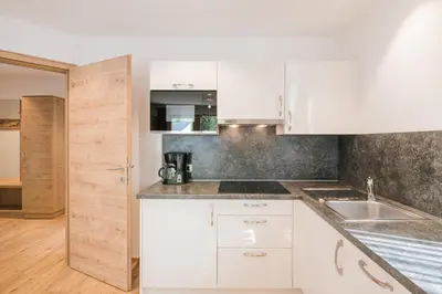 a kitchen with white cabinets and a sink at Apartments Sosaslong in Selva di Val Gardena