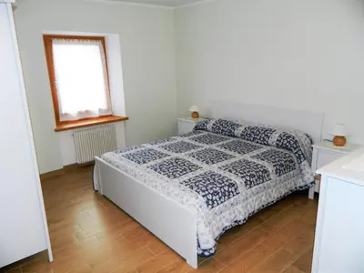 a white bedroom with a bed and a window at Appartamento Rosina, per 4/6 persone. In centro in Coredo