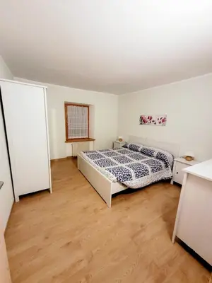 a bedroom with a bed and a wooden floor at Appartamento Rosina, per 4/6 persone. In centro in Coredo