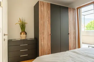 a bedroom with a wooden closet and a dresser at Ferienwohnung mit Garage, Fahrradraum und sehr großer sonnenverwöhnten Terrasse in Lagundo