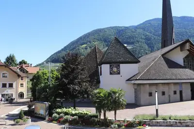 a church with a clock on the side of it at Ferienwohnung mit Garage, Fahrradraum und sehr großer sonnenverwöhnten Terrasse in Lagundo