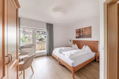 a bedroom with a bed and a desk and a window at Hotel Oberwirt in Velturno