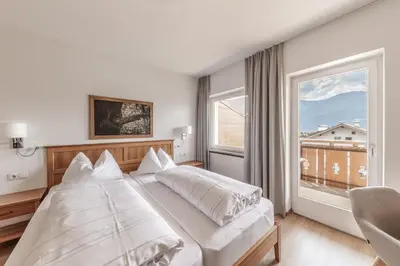 a bedroom with a large bed and a large window at Hotel Oberwirt in Velturno