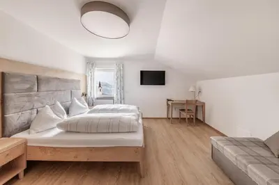 a bedroom with a large bed and a couch at Hotel Oberwirt in Velturno