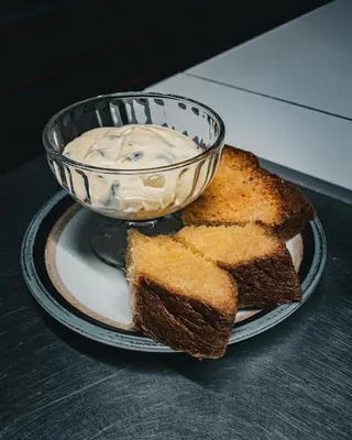 a plate with a bowl of cream cheese and bread at Pension Dolomieu in Santa Cristina in Val Gardena