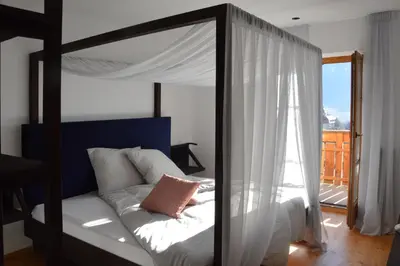 a bedroom with a canopy bed and a balcony at Apartment Pyrus in Tirolo