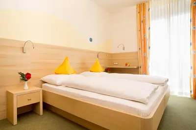 a bedroom with a large bed with white sheets and yellow pillows at Hotel Gruberhof in Merano