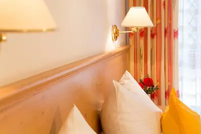 a couch with pillows next to a window with a lamp at Hotel Gruberhof in Merano