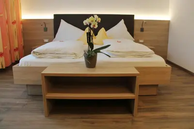 a bed with a table with a vase of flowers on it at Hotel Gruberhof in Merano