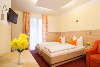 a hotel room with a bed and a vase of flowers at Hotel Gruberhof in Merano