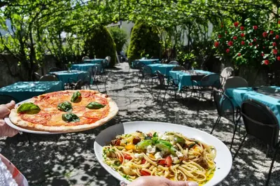 a table with two plates of pasta and a pizza at Hotel Villa Mayr Rooms & Suites in Brixen