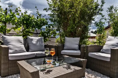 a patio with wicker chairs and a table with wine glasses at Hotel Villa Mayr Rooms & Suites in Brixen